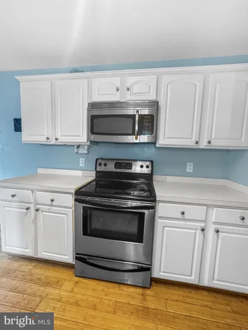 a kitchen with granite countertop a stove a microwave and white cabinets