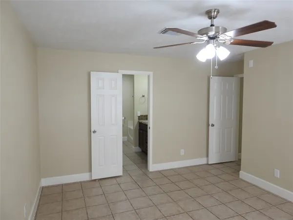 a view of an empty room and chandelier fan