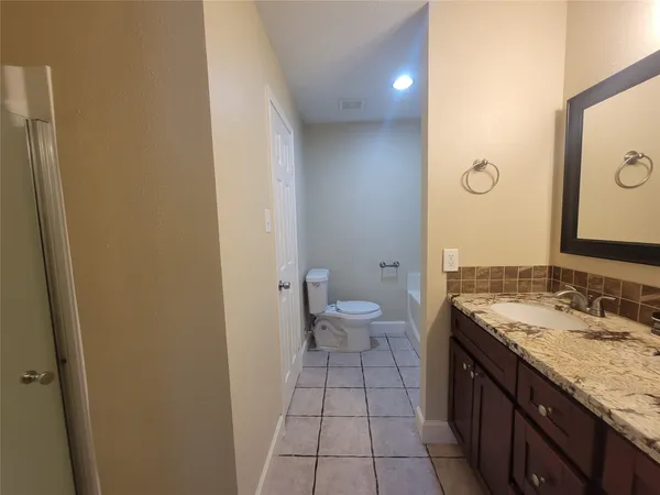a spacious bathroom with a granite countertop sink a toilet and a mirror
