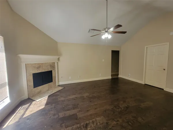 a view of an empty room with chandelier fan and fire place