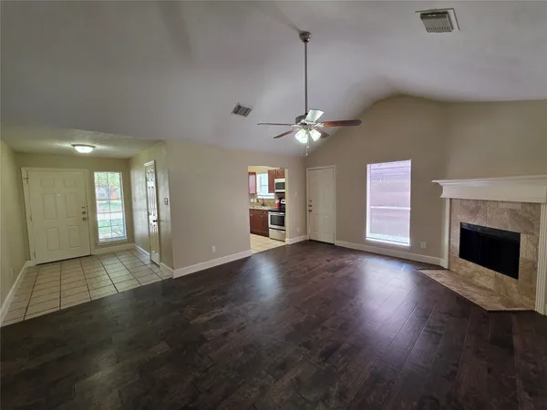 an empty room with wooden floor fireplace and windows