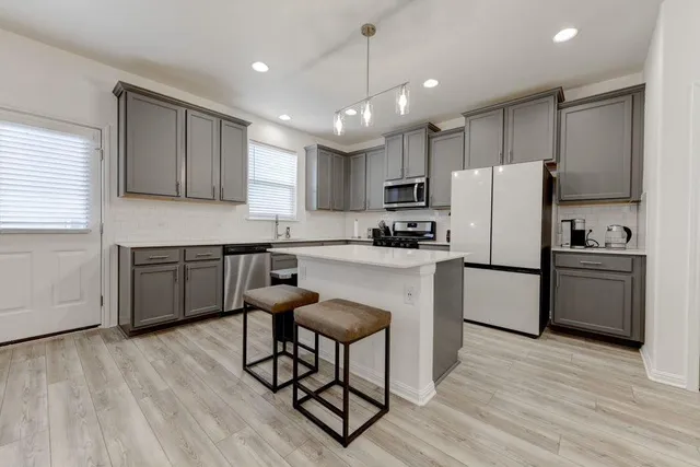 a kitchen with granite countertop a center island stainless steel appliances cabinets and a window