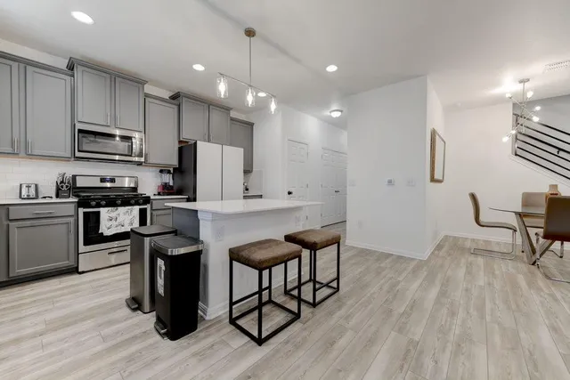 a kitchen with stainless steel appliances kitchen island granite countertop a table chairs refrigerator and microwave