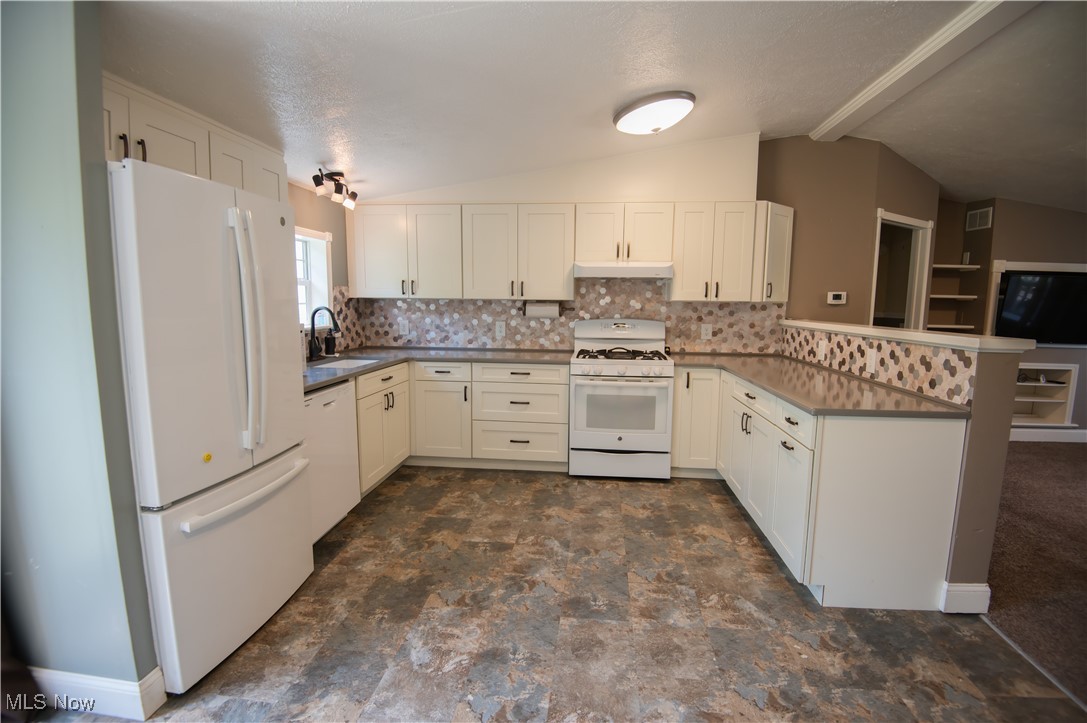 4594 Center Road Andover, OH 44003 - Photo 5 of 39 Kitchen featuring white appliances, a peninsula, decorative backsplash, and white cabinetry