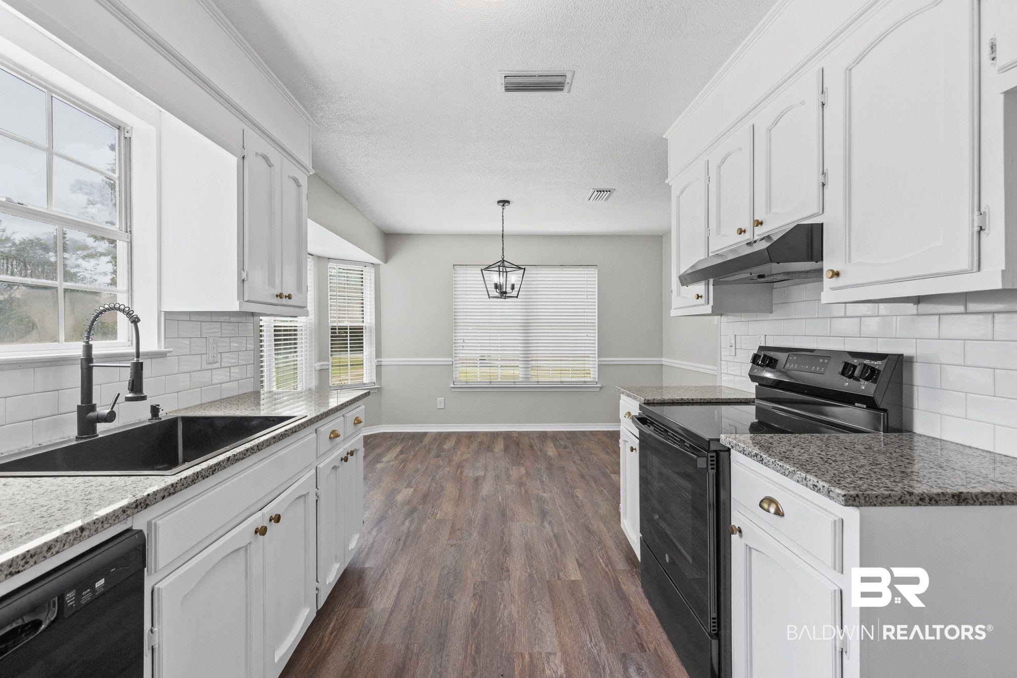 1301 Repoll Road Mobile, AL 36695 - Photo 6 of 21 Bright kitchen featuring white cabinetry with gold-tone hardware, granite-style countertops, and a subway tile backsplash