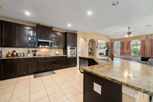 a large kitchen with granite countertop a large counter top stainless steel appliances and cabinets