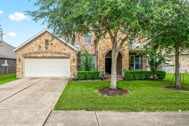 a view of a house with a yard and large tree