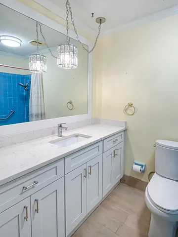 a bathroom with a granite countertop sink a toilet and a mirror