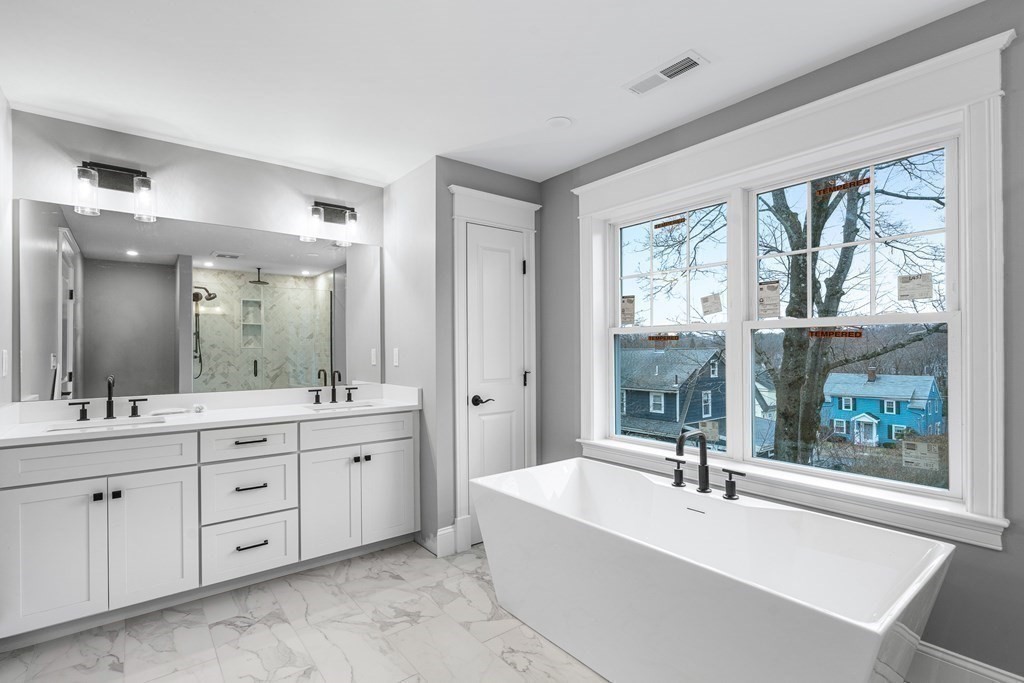 49 Allen Road Winchester, MA 01890 - Photo 23 of 38 a bathroom with a double vanity sink a large mirror a bathtub and next to a window