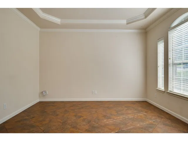 a view of an empty room with wooden floor and windows