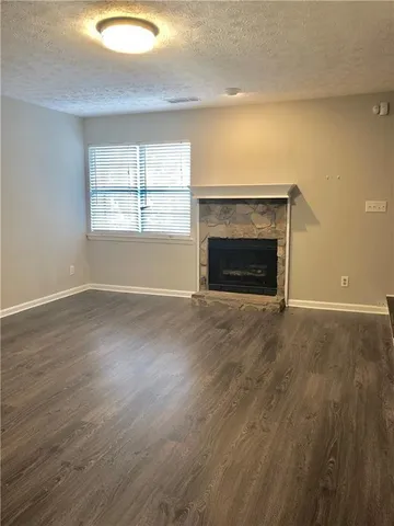 an empty room with wooden floor fireplace and windows
