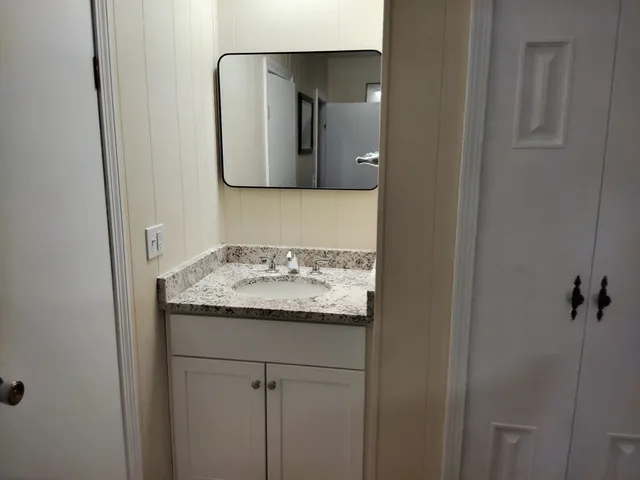 a bathroom with a granite countertop sink and mirror