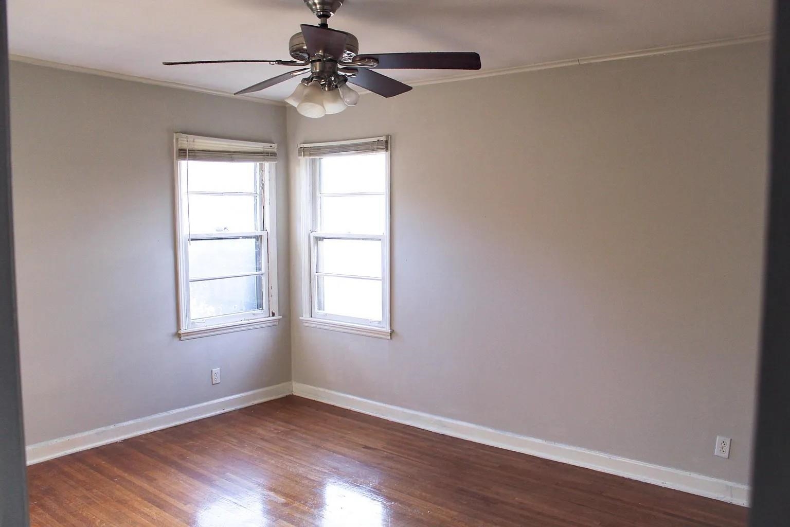 1606 Sea Isle Road Memphis, TN 38117 - Photo 5 of 7 an empty room with wooden floor chandelier fan and windows