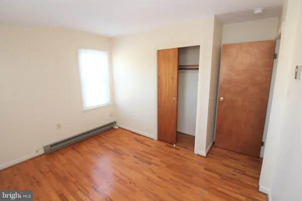 an empty room with wooden floor and closet