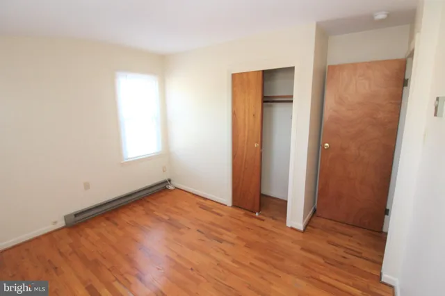 an empty room with wooden floor and closet