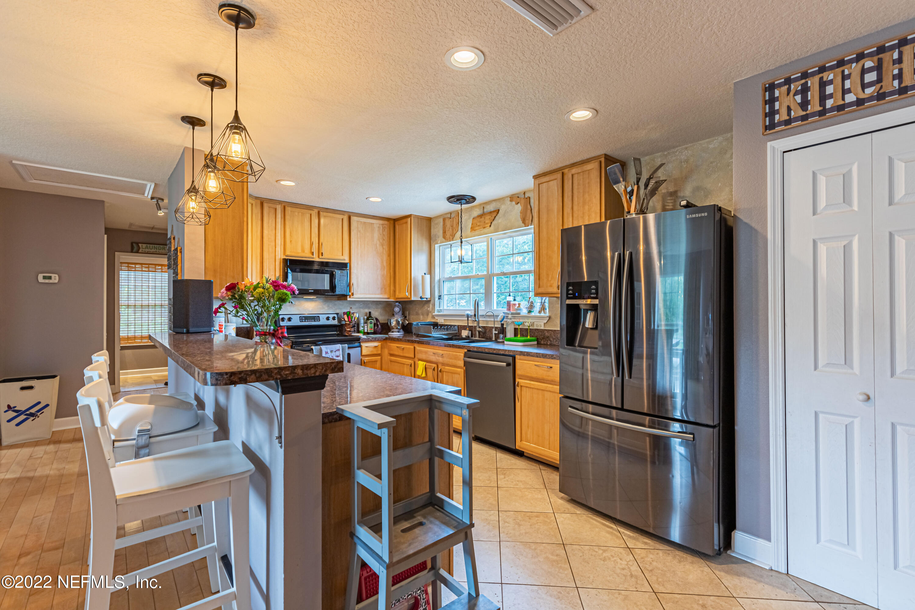 1830 Bennett Road St. Augustine, FL 32092 - Photo 9 of 45 a kitchen with stainless steel appliances a refrigerator a stove a sink dishwasher and a dining table with wooden floor