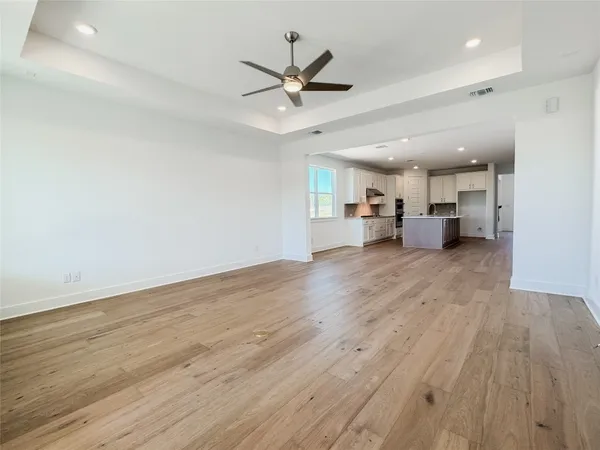 a view of a livingroom with a kitchen island wooden floor and a ceiling fan