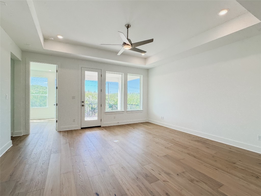 712 Iron Willow Loop Dripping Springs, TX 78620 - Photo 7 of 30 an empty room with wooden floor ceiling fan and windows