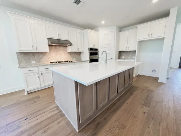 a kitchen with a sink a stove cabinets and wooden floor