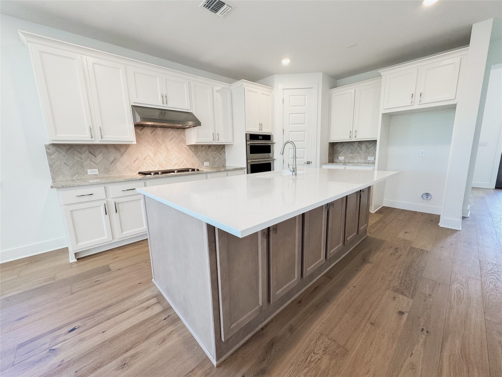 712 Iron Willow Loop Dripping Springs, TX 78620 - Photo 8 of 30 a kitchen with a sink a stove cabinets and wooden floor