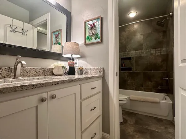 a bathroom with a granite countertop sink a mirror and shower