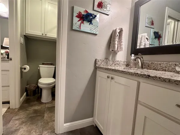 a bathroom with a granite countertop sink a toilet and a mirror