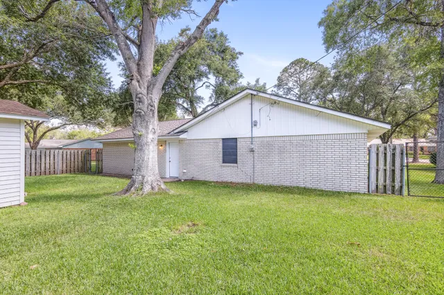 a house that has a big yard with wooden fence and a large tree
