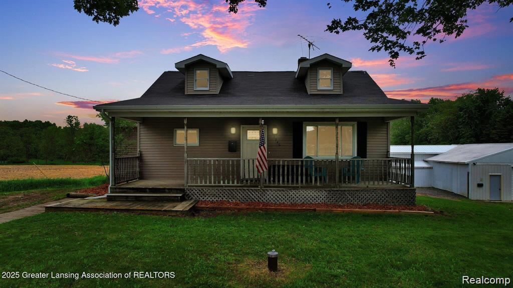 1246 House Road North Webberville, MI 48892 - Photo 1 of 22 Cape Cod style home featuring a covered front porch with railings, dormer windows, and a detached outbuilding