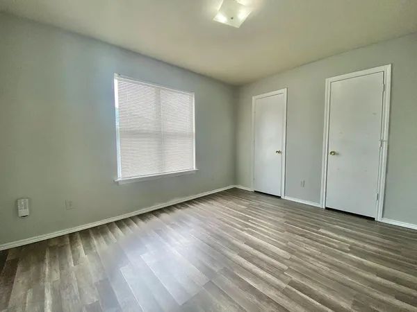 an empty room with wooden floor and windows