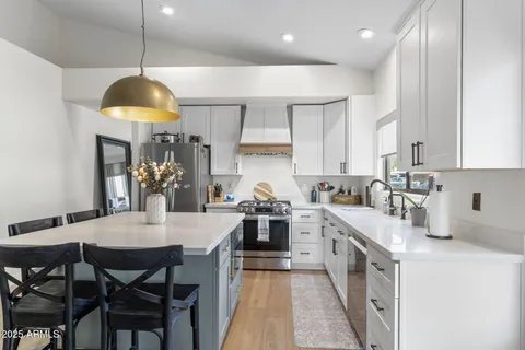 a kitchen with stainless steel appliances a dining table chairs and white cabinets