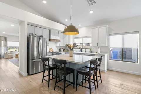 a kitchen with stainless steel appliances granite countertop a refrigerator a sink a stove a dining table and chairs