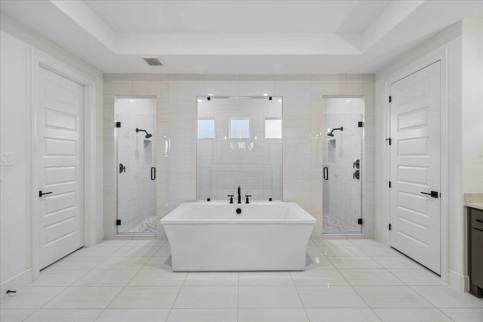 28015 Royal Swan Lane Spring, TX 77386 - Photo 16 of 25 Luxurious primary bathroom featuring a freestanding soaking tub centered between dual walk-in glass showers, creating a stunning spa-like retreat with elegant finishes throughout.