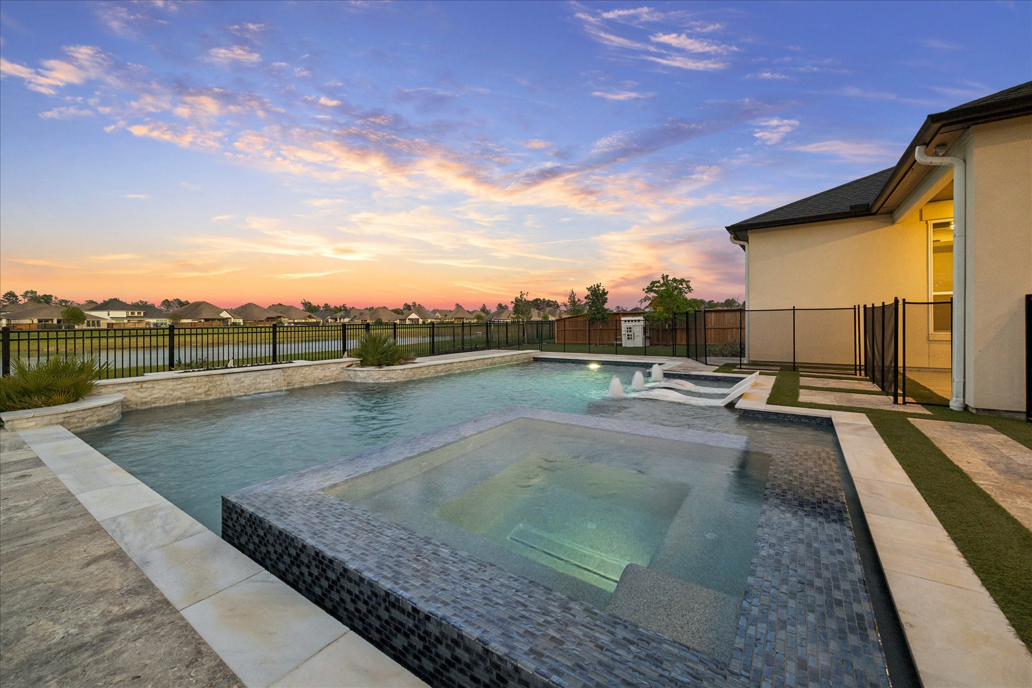 28015 Royal Swan Lane Spring, TX 77386 - Photo 2 of 25 Stunning resort-style pool and spa overlooking the lake, featuring water features, tanning ledge, and beautiful sunset views.