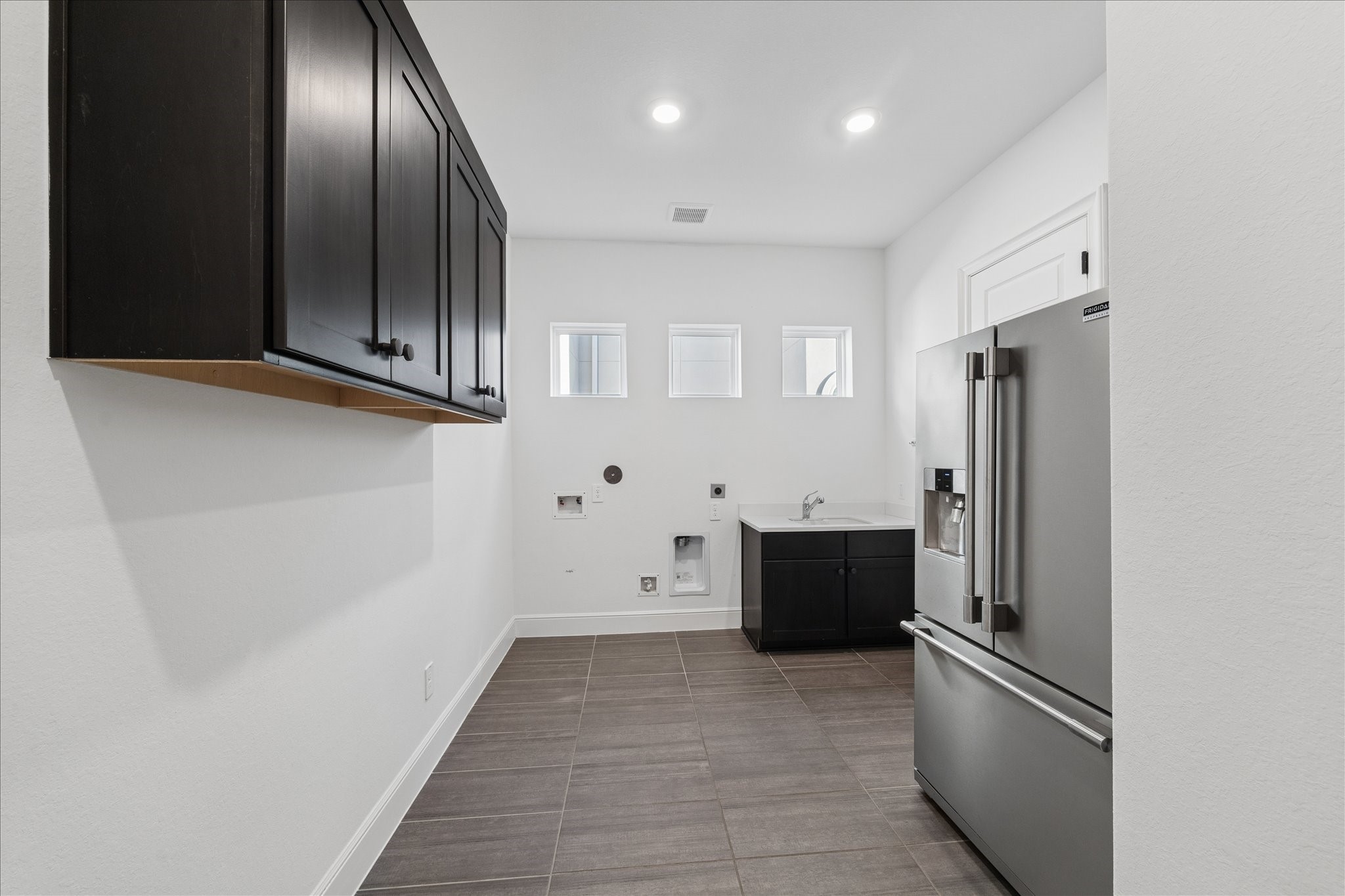 28015 Royal Swan Lane Spring, TX 77386 - Photo 21 of 25 Spacious laundry room with upper cabinetry for storage, utility sink, and space for a secondary refrigerator or additional appliances.