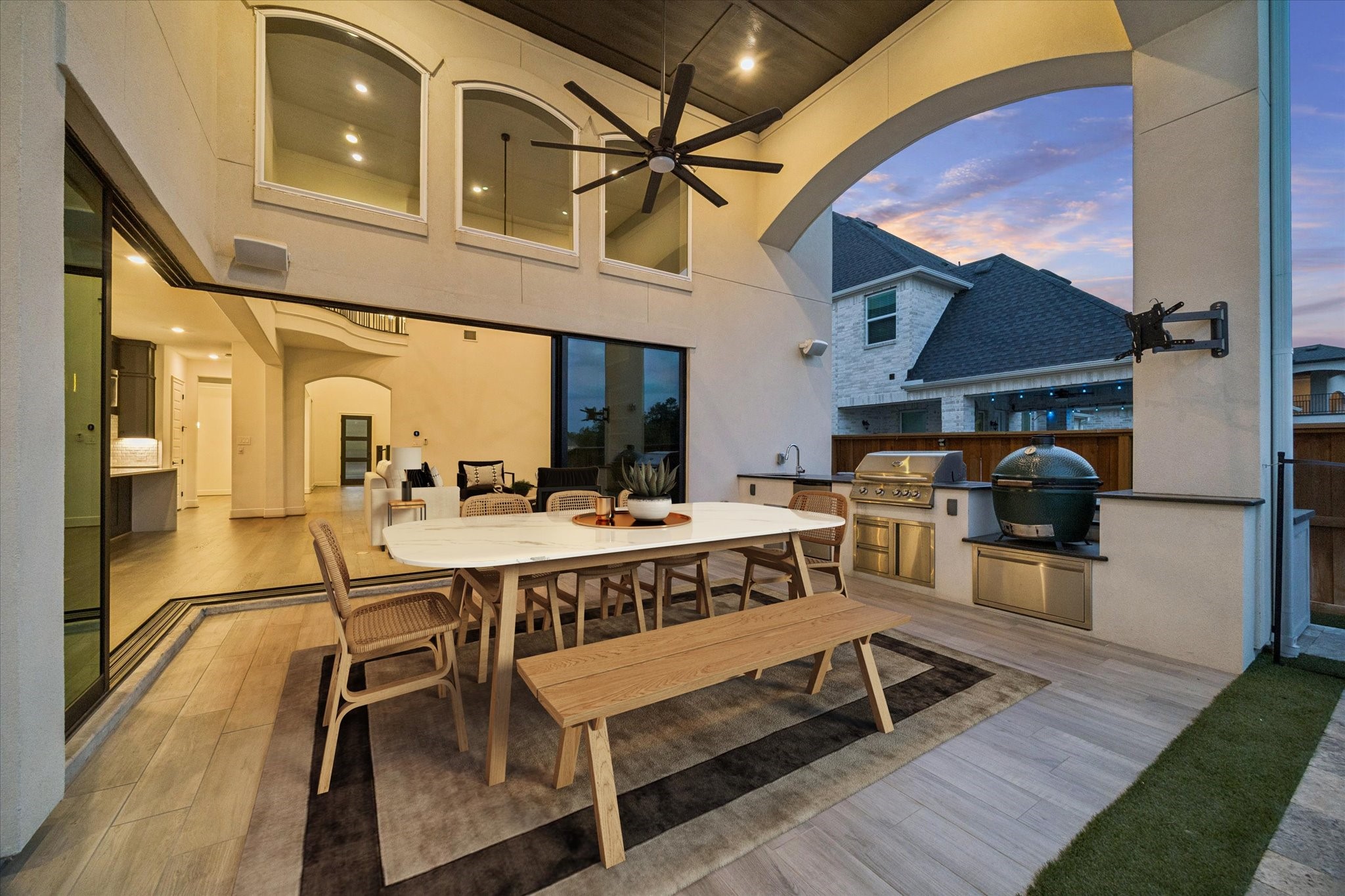 28015 Royal Swan Lane Spring, TX 77386 - Photo 22 of 25 Covered outdoor living space with soaring ceilings, expansive arched opening, and seamless indoor-outdoor flow. Features a built-in grill, Big Green Egg, dining area, and spacious seating—perfect for entertaining. *Virtually Staged