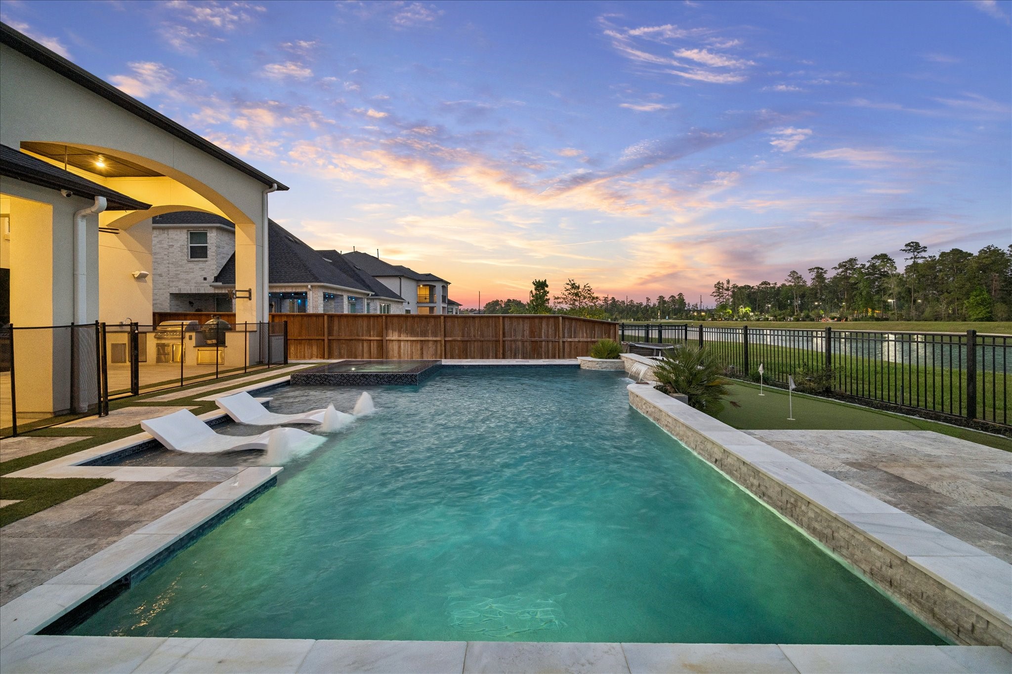 28015 Royal Swan Lane Spring, TX 77386 - Photo 23 of 25 Beautiful resort-style pool and spa overlooking the lake, complete with tanning ledge, water features, a turf putting green, and a built-in mosquito misting system for comfortable outdoor living.