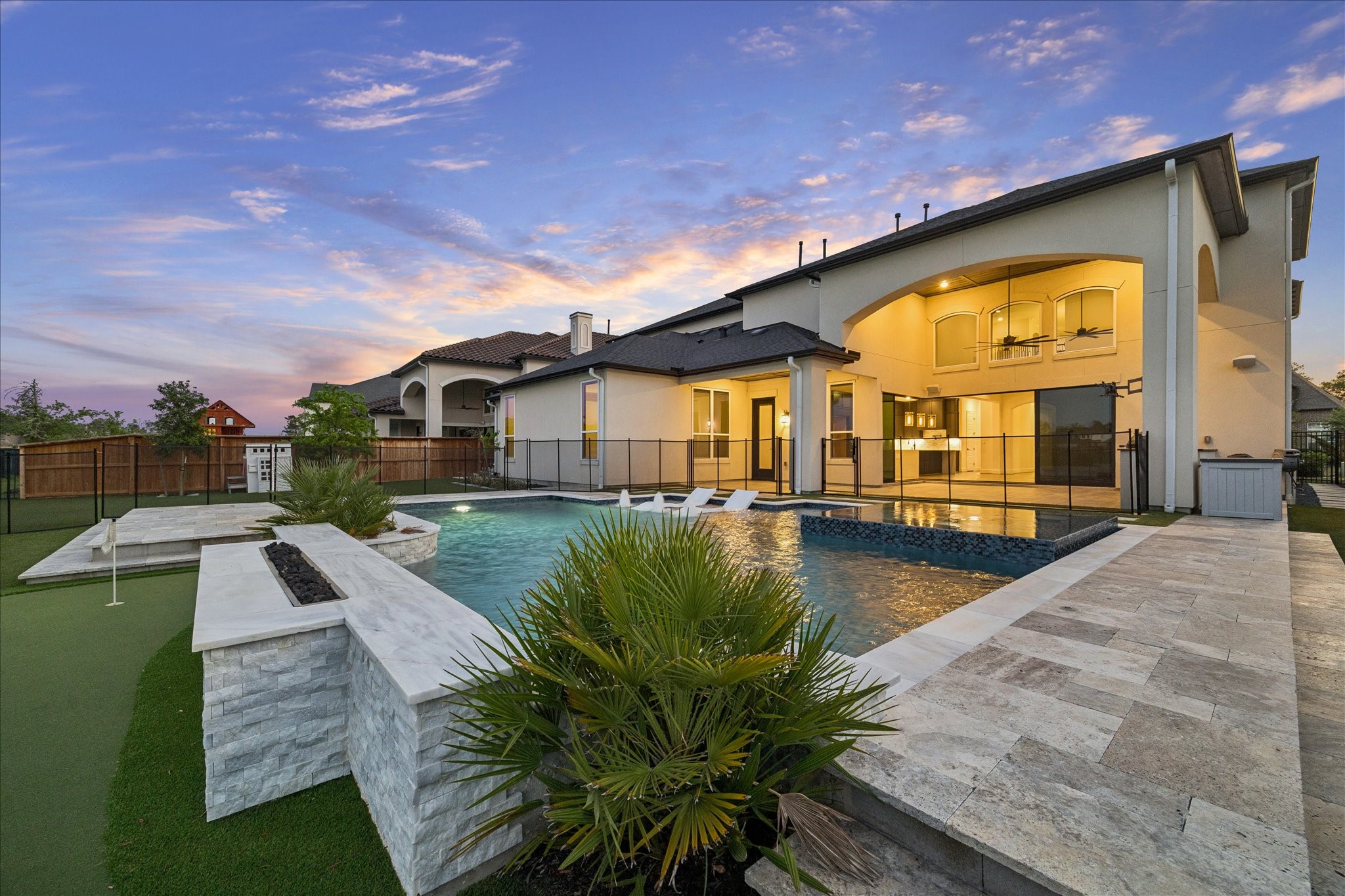 28015 Royal Swan Lane Spring, TX 77386 - Photo 24 of 25 Resort-style backyard featuring a beautiful pool, spacious patio areas, and expansive outdoor living space, complemented by a turf yard with a private putting green—perfect for relaxing, entertaining, and enjoying the outdoors.