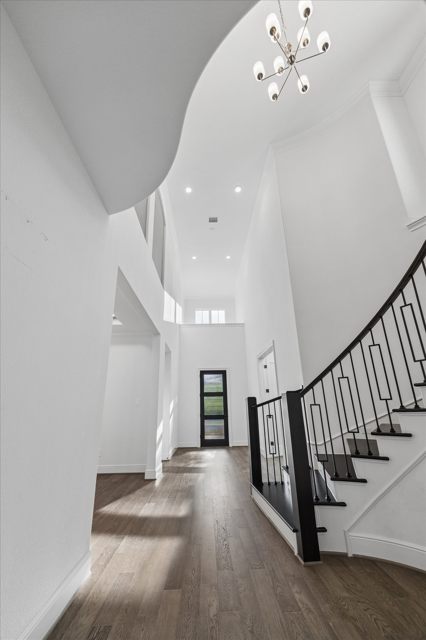 28015 Royal Swan Lane Spring, TX 77386 - Photo 6 of 25 Elegant entry hallway with soaring ceilings, abundant natural light, rich wood flooring, and a dramatic staircase that creates a bright and sophisticated first impression.