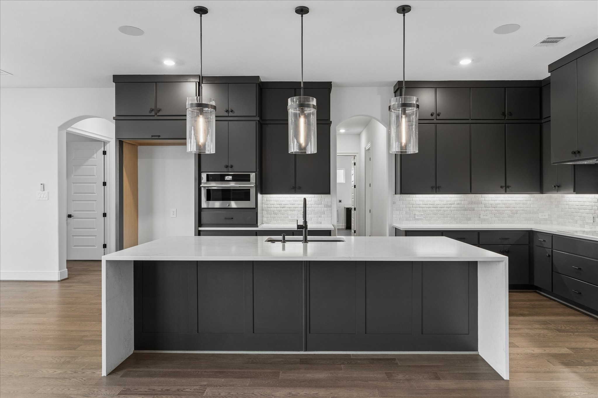 28015 Royal Swan Lane Spring, TX 77386 - Photo 9 of 25 Stunning chef’s kitchen featuring a large island with seating, sleek cabinetry, stainless steel appliances, designer pendant lighting, and abundant storage, all complemented by clean finishes and a spacious layout ideal for cooking and entertaining.