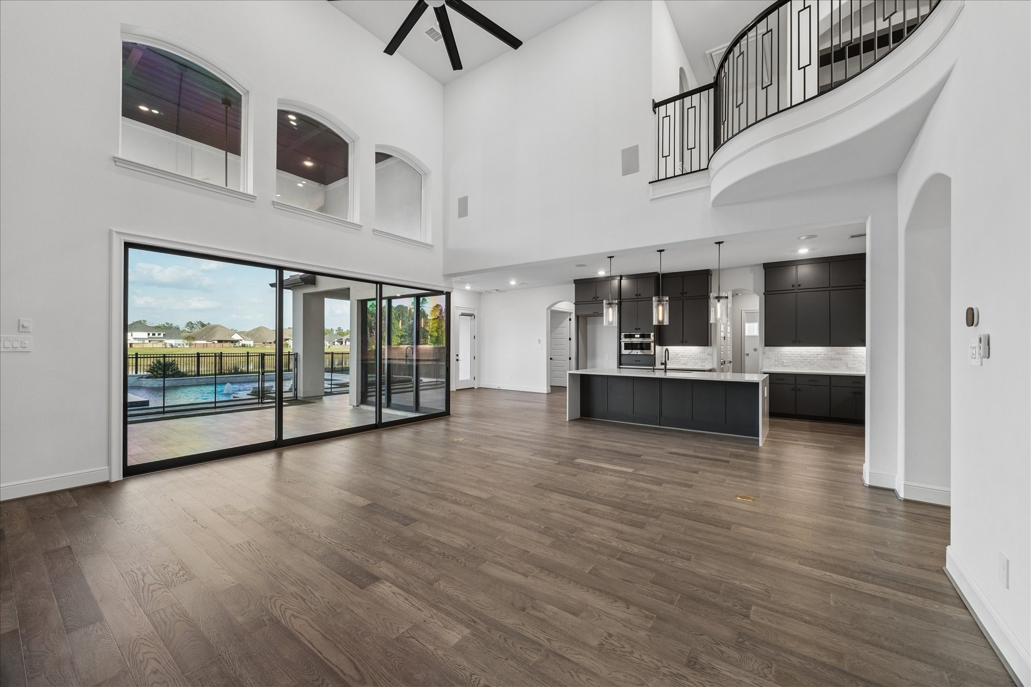 28015 Royal Swan Lane Spring, TX 77386 - Photo 10 of 25 Expansive open-concept living area with soaring ceilings, a large island kitchen, and corner sliding doors that open to the outdoor living space and pool, creating seamless indoor–outdoor living.