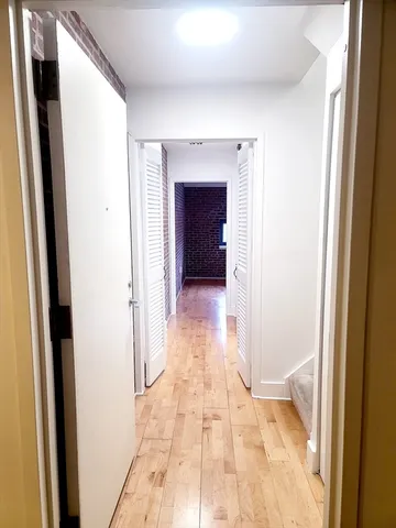 a view of a hallway with wooden floor and a living room