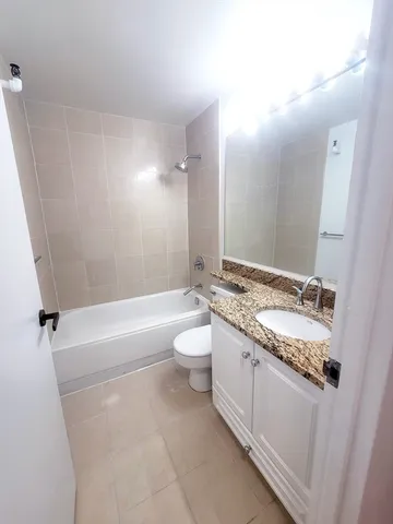 a bathroom with a granite countertop sink a toilet and tub