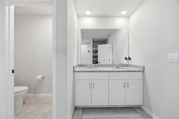 a bathroom with a granite countertop sink a toilet and a mirror