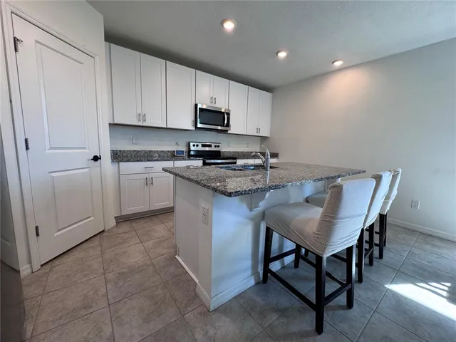 a kitchen with stainless steel appliances granite countertop a table chairs sink and cabinets