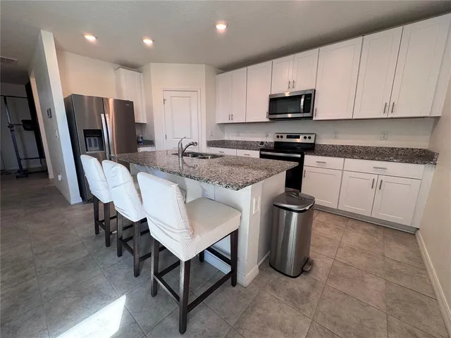 a kitchen with stainless steel appliances granite countertop a stove a sink dishwasher a refrigerator and a microwave