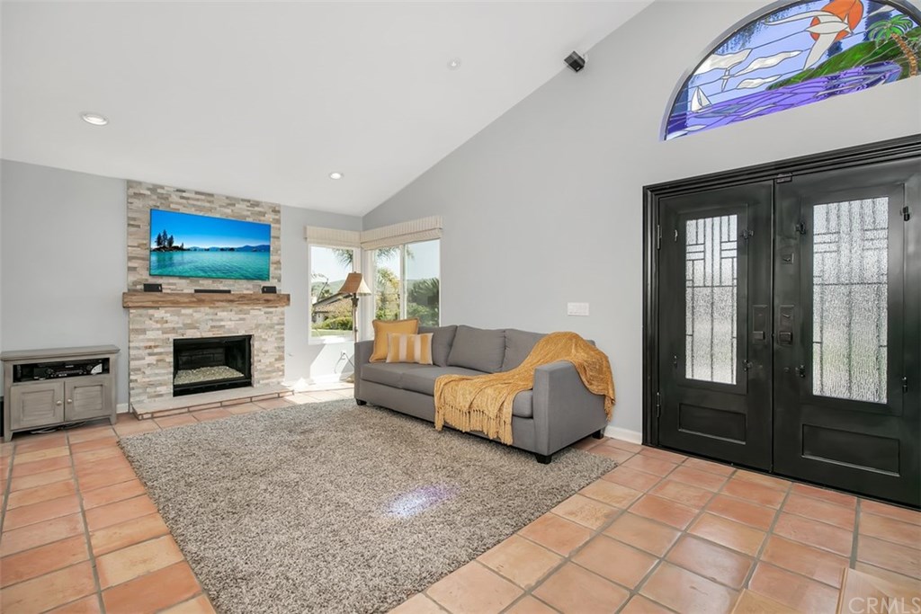 1306 Altura San Clemente, CA 92673 - Photo 3 of 28 Welcome home to your inviting front room with a beautiful stone fireplace with designer glass. The spectacular metal front doors have privacy glass that open up to a enjoyable ocean breeze. Yes, that is a view of the hills.