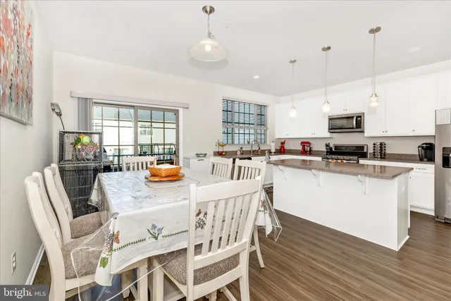 a kitchen with stainless steel appliances granite countertop a stove top oven a sink a dining table and chairs with wooden floor