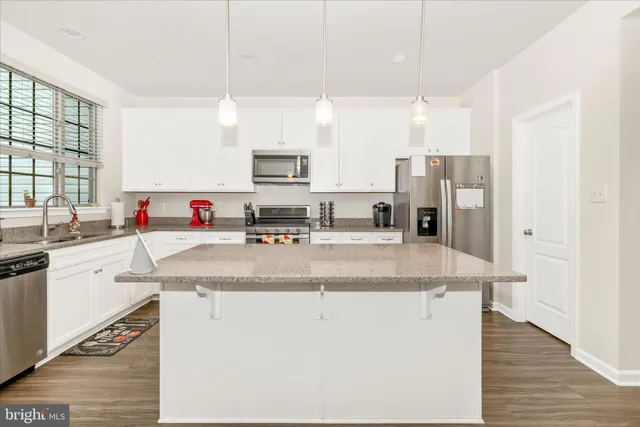 a kitchen with kitchen island granite countertop a sink appliances and cabinets