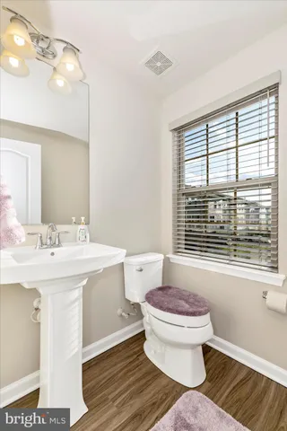 a bathroom with a sink toilet a large mirror and a window