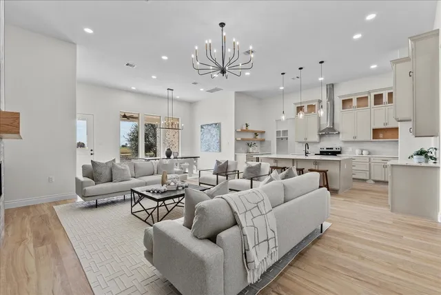 a living room with furniture kitchen view and a chandelier